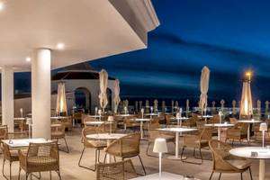 Außenbereich des Guayarmina Princess Hotels bei Nacht mit Tischen und Stühlen.