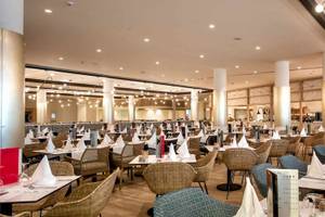 Innenbereich des Restaurants im Guayarmina Princess Hotel mit runden Tischen und Stühlen, dekorativen Lichtern und Holzboden.