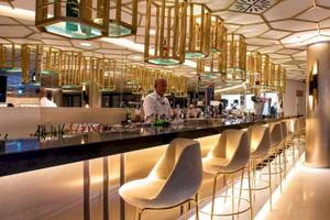 Innenansicht der Bar im Guayarmina Princess Hotel mit goldenen Kronleuchtern und modernen Stühlen.