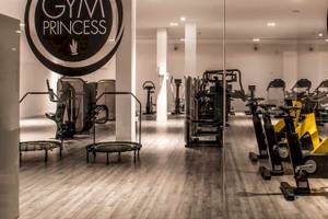 Innenansicht des Gyms der Guayarmina Princess mit diversen Fitnessgeräten und einem Holzboden.