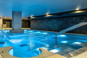 Innenpool des Guayarmina Princess Hotels mit blauem Wasser und beleuchteten Stufen.