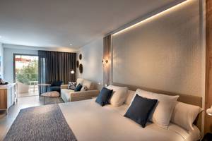 Guyarmiina Princess Hotel Schlafzimmer mit Doppelbett, Kissen, Couch und Glastür.