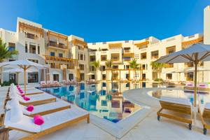 Außenbereich des Sifawy Boutique Hotels mit Swimmingpool, Sonnenliegen und Sonnenschirmen.