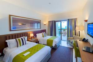 Doppelzimmer im Sifawy Boutique Hotel mit zwei Betten, Fernseher, Schreibtisch und Balkon.