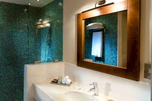 Badezimmer im Sifawy Boutique Hotel mit blauen Fliesen und einem großen Spiegel.