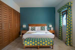 Schlafzimmer im Sifawy Boutique Hotel mit blauer Wand, Bett, Nachttischen und Holzschrank