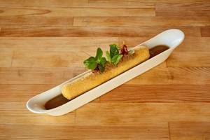 Gebäck in einer weißen Schüssel mit Sauce auf einem Holztisch