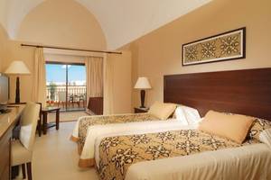 Hotelzimmer im JAZ Neo Dar El Madina mit zwei Betten, Fernseher, Schreibtisch und Balkon.