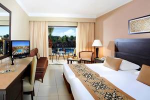 Hotelzimmer im Jaz Dar El Madina mit Balkon, Fernseher, Schreibtisch und Möbeln.