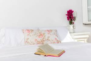 Ein Bett mit weißen Kissen und einem offenen Buch auf der Bettdecke.