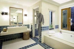 Badezimmer im Robinson Khao Lak Hotel mit Badewanne, Waschbecken und blauen Fliesen.