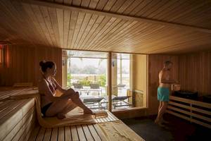 Eine Frau sitzt in der Sauna des Robinson Khao Lak Hotels, während ein Mann daneben steht.