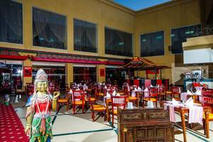 Innenansicht des Restaurants mit roten Sesseln und Buddha-Statue.