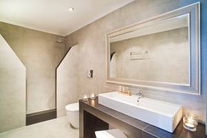 Badezimmer von Agali Houses mit weißem Waschbecken und silbernem Spiegel.
