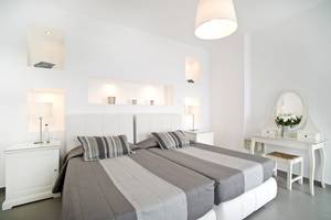 Doppelbett-Zimmer im Agali Houses Hotel mit weißen Möbeln und grauen Laken.