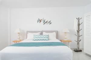 Schlafzimmer mit Bett, Lampen und Vogel Wandkunst in Agali Houses