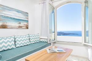 Innenraum von Agali Houses mit einem Sofa, einem offenen Fenster und Meerblick.