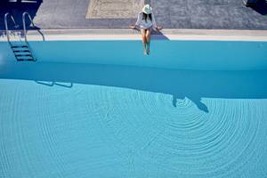 Eine Frau springt von der Poolkante in das Schwimmbad des Agali Houses Hotels.