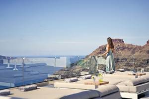 Aussicht von der Terrasse des Agali Houses Hotels mit Frau, die auf das Meer schaut.