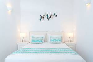 Schlafzimmer von Agali Houses mit weißen Wänden, einem Doppelbett und zwei Nachttischen mit Lampen.