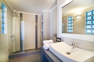 Badezimmer von Agali Houses mit Dusche, Waschbecken und Spiegel.
