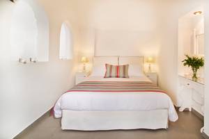 Schlafzimmer der Agali Houses mit einem Bett, zwei Nachttischen und weißen Wänden.