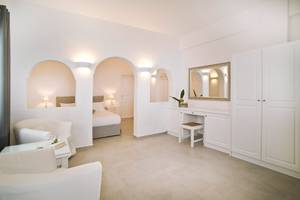Innenansicht der Suite im Agali Houses Hotel mit weißen Möbeln, einem großen Bett und einer hellen Atmosphäre.