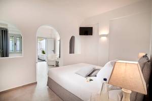 Innenansicht eines Zimmers der Agali Houses mit weißem Bett, Tisch, Lampe und Fernseher.