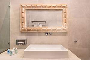 Badezimmer im Agali Houses Hotel mit zeitgenössischem Design, einem weißen Waschbecken und einem gerahmten Spiegel.