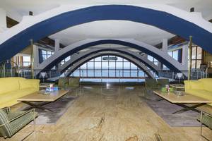 Hotellobby mit gelben Sofas und Meerblick durch große Glasfenster