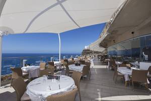 Hoteldachterrasse mit Blick auf das Meer, gedeckte Tische und Stühle.