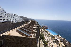 Aussicht auf das Gloria Palace Amadores Thalasso & Hotel mit Solarpanelen, einem Swimmingpool und Blick aufs Meer.