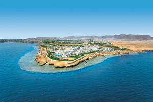 Luftaufnahme des Sharm Club Beach Resorts, umgeben von Wasser und weißen Gebäuden.