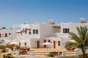 Außenbereich des Sharm Club Beach Resorts mit weißen Gebäuden und Palmen