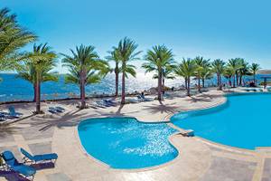 Poolbereich des Sharm Club Beach Resorts mit blauem Wasser und Palmen.