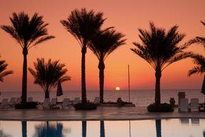 Sonnenuntergang am Pool von Sharm Club Beach Resort mit Palmen und Strandliegen.