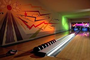 Eine Bowlingbahn im Hotel mit bunten Wandmalereien und Bowlingkugeln in einer Reihe.