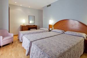 Doppelzimmer im Gargallo Rialto Hotel mit zwei Betten, Nachttischen und einem rosa Stuhl.