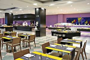 Innenansicht des Restaurants im Gran Canaria Princess Hotel mit geometrischem Boden, gepolsterten Stühlen und Tischen sowie Buffets.