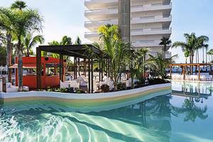 Poolbereich des Gran Canaria Princess Hotels mit Lounge-Ecke und hohem Gebäude im Hintergrund.