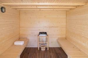 Innenansicht der Sauna im Gran Canaria Princess Hotel mit Holzbänken, einem Holzofen und Handtüchern.