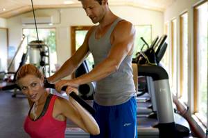 Ein Fitnesstrainer hilft einer Frau im Gym, Übungen durchzuführen.