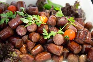 Nahaufnahme von gegrillten Würstchen mit Tomaten und Petersilie