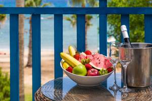Ein Balkon des Callisto Holiday Village mit einer Obstschale, zwei Weingläsern und einer Flasche Champagner.