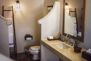 Innenansicht eines Badezimmers im Saree Samui Resort mit Toilette, Waschbecken und Spiegel.