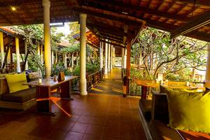 Außenbereich des Saree Samui Resorts mit gelben Kissen und Holztischen.