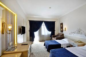 Doppelzimmer im Club Yali Hotels & Resort mit zwei Betten, Fernseher und einem Schreibtisch.
