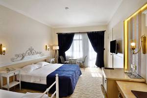 Schlafzimmer im Club Yali Hotels & Resort mit zwei Betten, Schreibtisch und Fernseher.