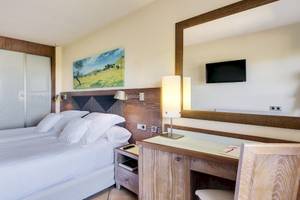 Hotelzimmer im Occidental Playa de Palma mit einem Bett, Schreibtisch, Spiegel und Lampe.