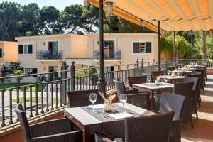 Außenterrasse des Occidental Playa de Palma Hotels mit Tischen und Stühlen unter einem Sonnensegel.
